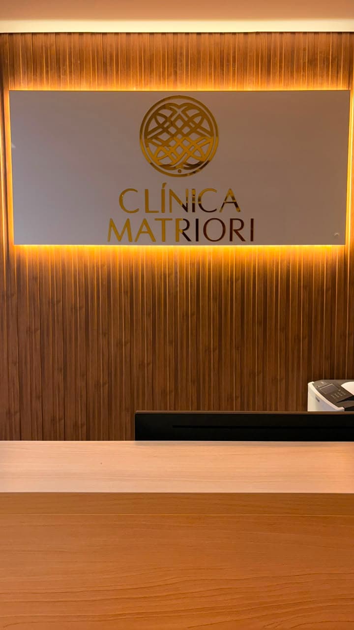 Recepção da Clínica Matriori, com o logo iluminado atrás do balcão